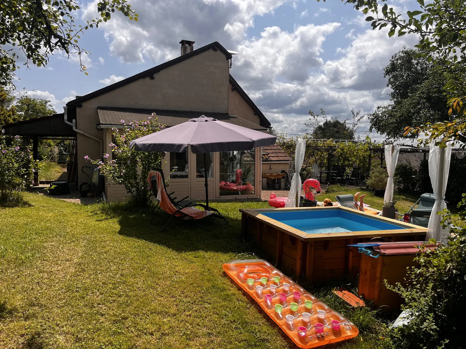 Plunge pool and sun deck in the sunny garden, with the house behind